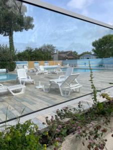 a view of a patio with white chairs and a pool at Lux in Saint-Pierre-dʼOléron