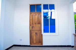 a wooden door and window on a white house at Ray Infinity Suites in Paje +4 photos