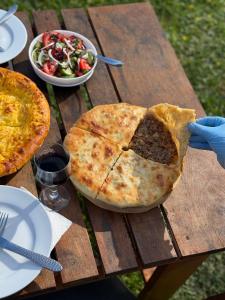 a table with two pizzas and a bowl of salad at Hotel Chubezeni in Mestia +31 photos