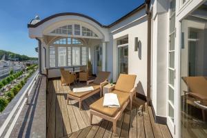 a balcony with chairs and tables on a building at Strandschloss Binz - Penthouse "Royal Beach" mit Sauna, Kamin, Terrasse, Meerblick in Binz