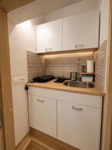 a kitchen with white cabinets and a sink at Apartment Alee in Lesce