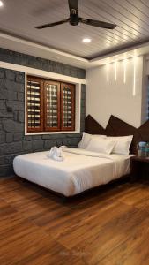 a bedroom with a large white bed with a brick wall at Birdwing Cottage, Munnar in Munnar