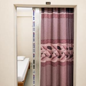 a window with a curtain in a bedroom at Jannat Residential Hotel in Atgaon