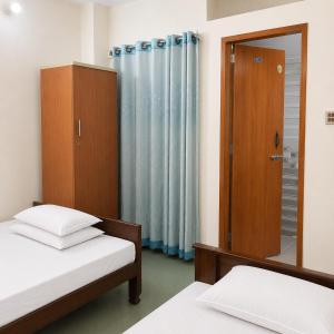 a bedroom with two beds and a mirror at Jannat Residential Hotel in Atgaon