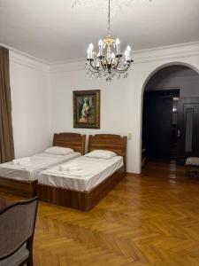 two beds in a room with a chandelier at Kobuleti apartment in Kobuleti