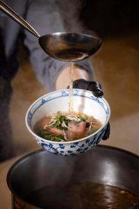 a person holding a bowl of soup with a spoon at JW Marriott Hotel Hanoi in Hanoi +198 photos