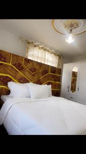 a white bed in a bedroom with a stone wall at Golden fortune Hotel apartment in Molyko