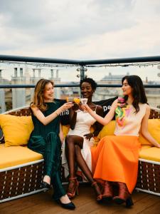 three women and a man sitting on a balcony with drinks at Aria Hotel Budapest by Library Hotel Collection in Budapest