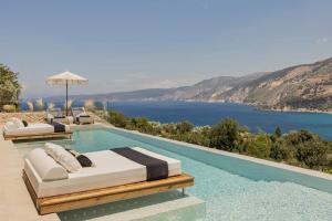a pool with two beds and a view of the water at Nekyra Villa in Zóla