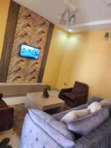 a living room with a couch and a tv on a wall at The Oasis in Ilorin