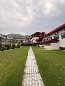 a grassy field with a pathway in front of some buildings at DANGWAL HoTEL in Srīnagar +25 photos