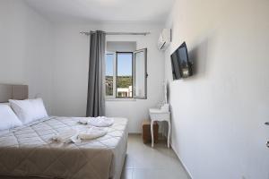 a white bedroom with a bed and a window at A&E Cretan Oasis in Loutra +33 photos