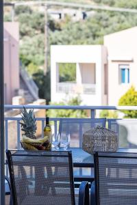 a table with a bowl of fruit and wine glasses on a balcony at A&E Cretan Oasis in Loutra