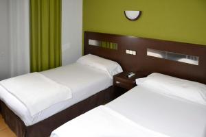 two beds in a room with green walls at Sercotel Las Estrellas in Ciempozuelos