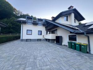 a white house with trash cans in a driveway at Alpine Forest Apartments in Radovljica +21 photos