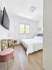 a white bedroom with a bed and a tv at Miami in Veliko Brdo