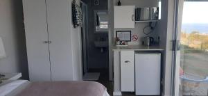 a small kitchen in a room with a bed and a window at View on 42 - Protea Room - Small cozy room with ocean view in Mossel Bay +12 photos