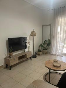 a living room with a flat screen tv on a table at Sea And Sand Apartment in Nea Kallikrateia