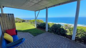 a porch with a chair and a view of the ocean at View on 42 - Protea Room - Small cozy room with ocean view in Mossel Bay