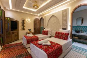 a hotel room with two beds and a tv at Riad Secret Mahjouba in Marrakesh +79 photos