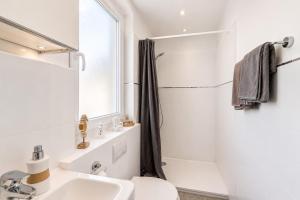 a white bathroom with a sink and a shower at Charmante Stadtwohnung im Zentrum in Wiesbaden +11 photos