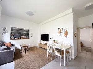 a white living room with a table and a couch at הפינה של טלי בנהריה - יחידות אירוח וספא בריאות in Nahariyya