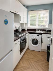 a kitchen with white cabinets and a washer and dryer at 2BR House By Cozy Quarters Property Management Contractors Accommodation Spennymoor With Parking in Spennymoor