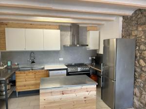a kitchen with a stainless steel refrigerator and wooden cabinets at Colònies Cadí - Cal Caló in Bellver de Cerdanya
