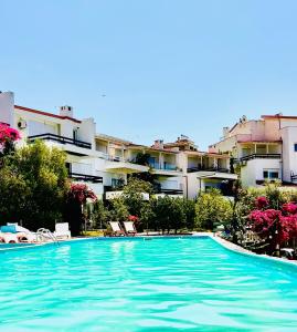 a swimming pool with chairs and buildings in the background at Olives Terrace B2A5 Apartment in Dhërmi