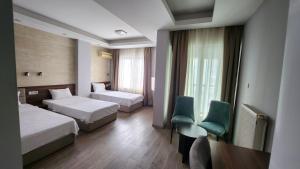 a hotel room with two beds and a table and chairs at Hotel Rile Men Blue in Niš