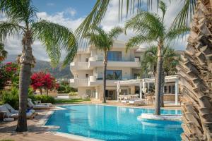 a view of a hotel with palm trees and a swimming pool at Parthenis Hotel & Suites in Malia