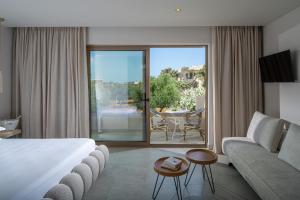 a hotel room with a bed and a couch and a patio at Parthenis Hotel & Suites in Malia +73 photos