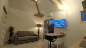 a living room with a couch and a desk and a tv at Pause au coeur des Côtes-Rôtie in Ampuis