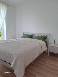 a white bedroom with a bed with green pillows at Garden House in Dég +5 photos