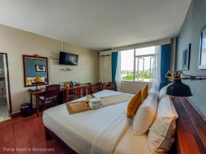 ein Hotelzimmer mit einem großen Bett und einem Schreibtisch in der Unterkunft Pakse hotel & Restaurant in Pakse