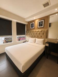 a bedroom with a large white bed and a desk at Sandpiper Hotel Singapore in Singapore