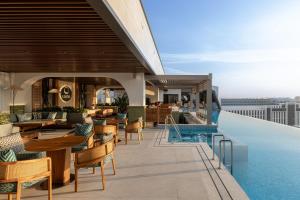a hotel rooftop with a pool and tables and chairs at Doubletree By Hilton Tashkent in Tashkent