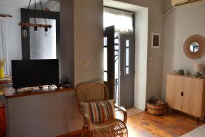 a living room with a chair and a flat screen tv at Coralia Nest Studio in Glossa