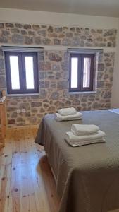 a bedroom with two beds and two windows at Stone house 2 in Líthion