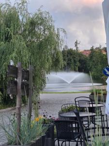 a table and chairs in front of a pond with a fountain at Apartament Lipowa Centrum in Mrągowo
