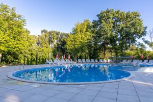 a swimming pool with chairs and tables and trees at Hotel PRESLAV in Golden Sands