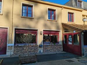 a building with red doors and windows on a street at Hotel O'Fun Art in Airvault