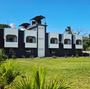 a black and white building with a grass field at MERED Haven Studio in Kilifi