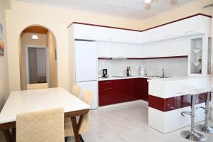 a kitchen with white counters and a table and chairs at Golden Berden Boutique Apart-Hotel in Sarandë +225 photos