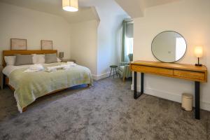 a bedroom with a bed with a mirror and a dresser at Maesteg Road - Large House - Sleeps 10 - Gateway to Afan Forest and Bike Trails in Dyffryn