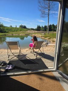 a little girl sitting in a chair next to a lake at Mullimaja in Treimani