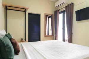 a bedroom with a white bed and two windows at Rooms at Calma Villa Panorama, Batu Malang in Batu