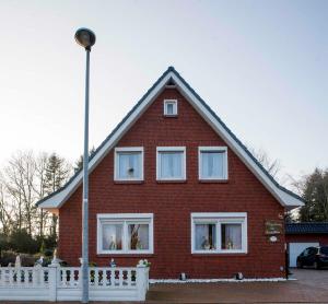 a red brick house with a white fence at Ferienwohnung Schoon, 85042 in Ostrhauderfehn