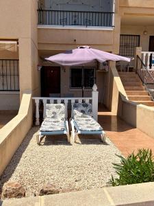 two chairs and an umbrella in front of a building at Tranquil Self Catering Golf Course Apartment in Alicante +20 photos