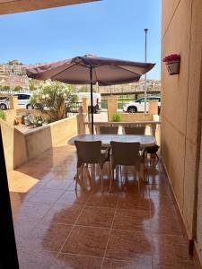 a table and chairs and an umbrella on a patio at Tranquil Self Catering Golf Course Apartment in Alicante